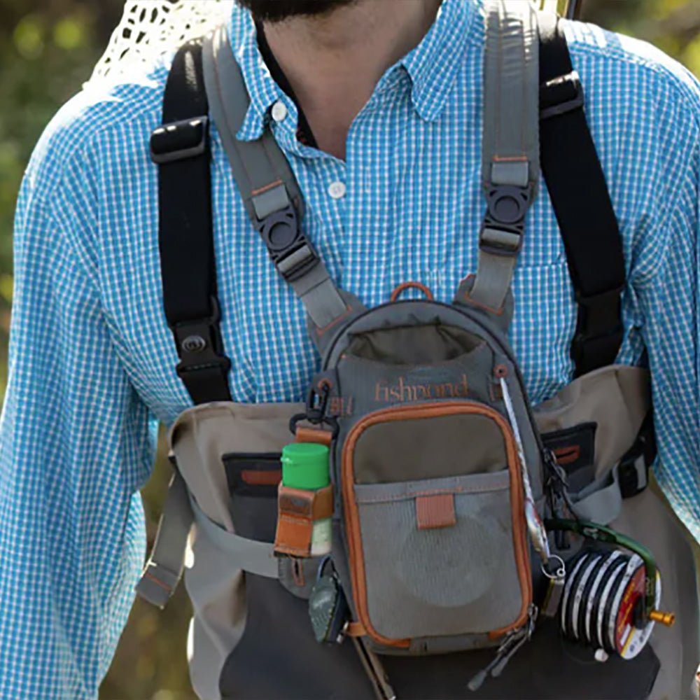 Shown is the Fishpond Canyon Creek Check Pack being worn by an angler with several tools and leader spools placed on the pack