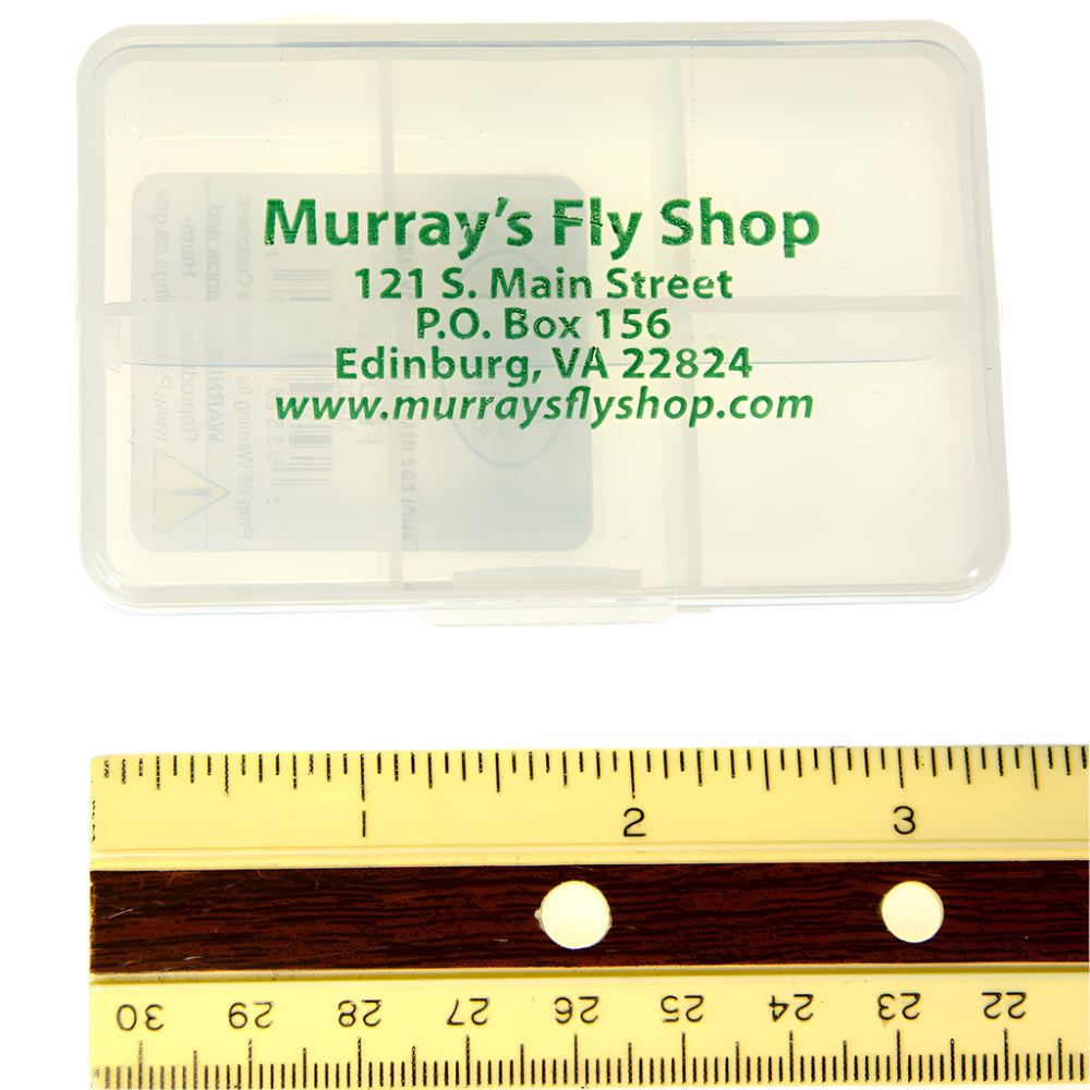 Shown is a polycarbonate clear Murray's Fly Shop fly box with 6 compartments and a ruler on a white background